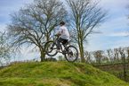 Kind springt mit Mountainbike über Hügel