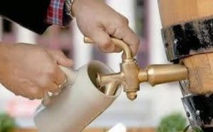 eine Person zapft sich ein Bier in einen Krug vom Holzfass