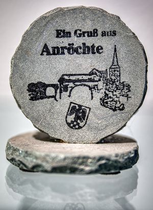 eine Runde Anröchterstein platte auf der ein Gruß aus Anröchte, das Anröchter Wappen und eine Kirche eingraviert ist