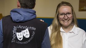 Christina Schulenberg steht neben einer Person mit dem logo des Theaters in Anröchte auf dem rücken
