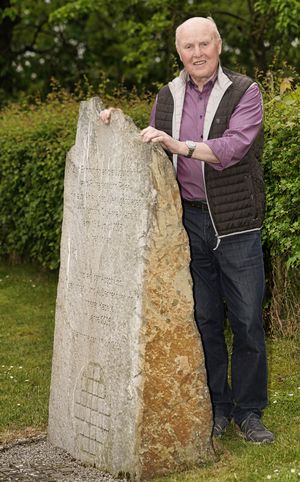 Joe schulde steht hinter Gedenkstein und stützt sich auf diesem ab