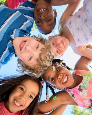 Fünf Kinder stehen um die Camara herum und schauen von oben hinab in die linse und lächeln